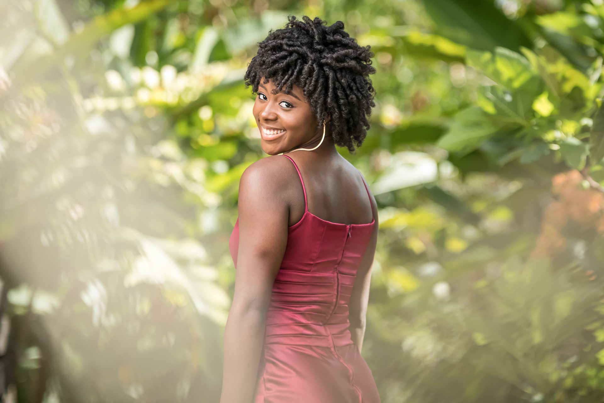 portrait of young Jamaican woman in red dress standing in garden taken by Gabre Cameron