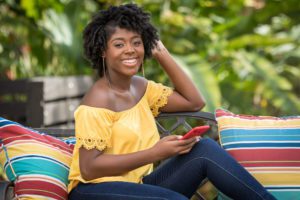 portrait of Jamaican female outdoors on bench with cell phone taken by Gabre Cameron